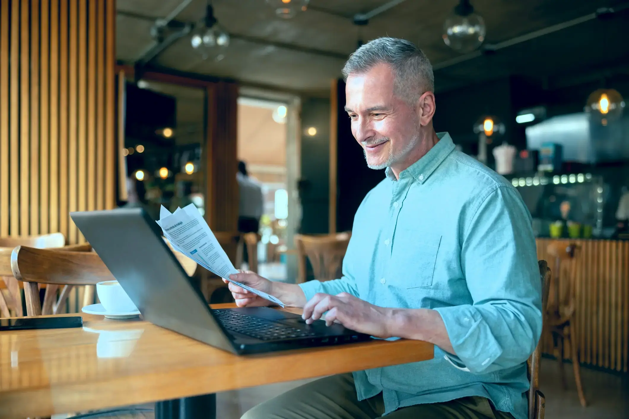 Businessman reviewing financial documents on laptop.