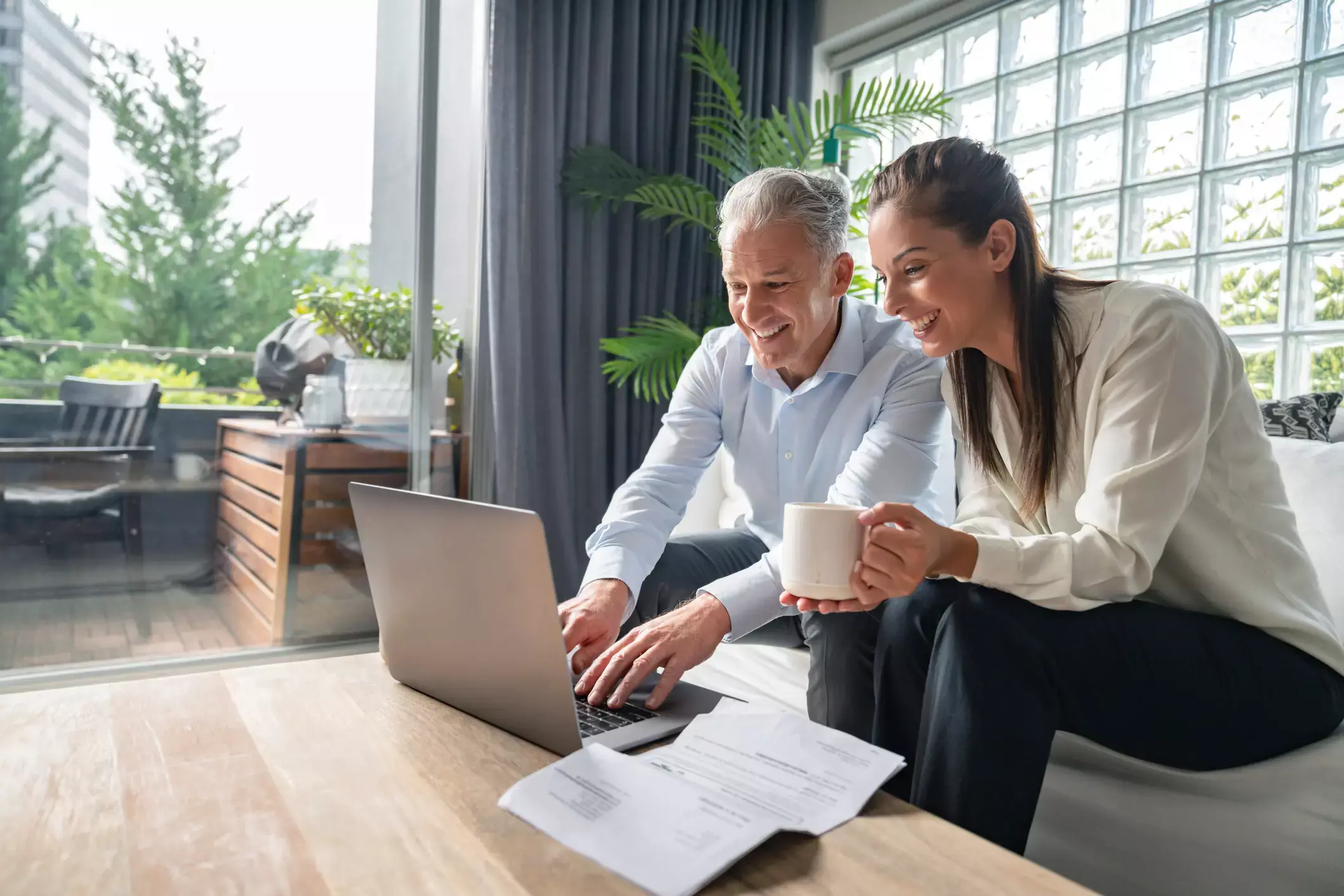 Senior businessman and young woman reviewing documents on laptop, discussing unsecured business loan options