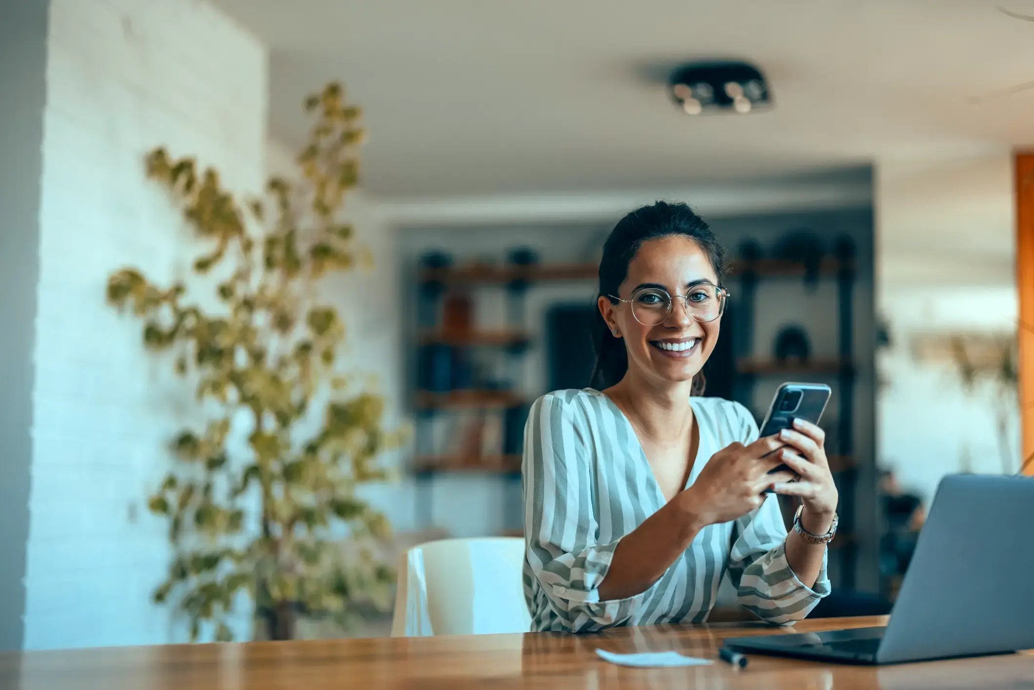 Businesswoman with phone and laptop researching business loans.